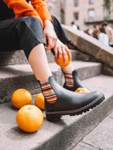 Botinetas de agua de mujer color negro, con suela track de tacón bajo y elásticos laterales con diseño de rayas multicolor. Cuenta con tirador trasero para facilitar su colocación.