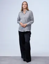 Camisa de satén estampado con diseño de cadenas en blanco y negro. Cuello con solapa, escote en V y abertura central con botones.