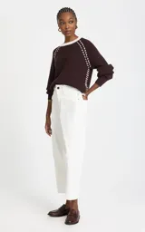Pantalón de pana color blanco, corte balloon de talle alto y silueta ancha ligeramente ajustada en los tobillos. Cuenta con bolsillos y cierre frontal con botón y cremallera.