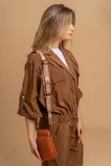 Bandolera compacta color rojo con textura de cuero, correa regulable y desmontable con diseño de rayas rojas y blancas. Cuenta con bolsillos frontales y cierre, interior forrado en tela.