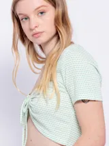 Top de manga corta con escote en V y fruncido ajustable con lazo en el centro, de tela texturizada con estampado de puntos pequeños.