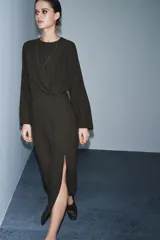 Vestido midi de Zara Woman Collection, color verde oscuro, con cuello redondo, manga larga y detalle de pliegues en el delantero. Presenta un corte recto con abertura frontal en el bajo y cierre lateral con cremallera oculta.