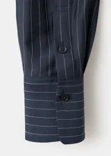 Camisa azul marino con diseño de rayas diplomáticas finas, cuello camisero clásico, mangas largas y cierre frontal con botones.