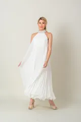 Vestido largo blanco de gasa plisada, sin mangas y con cuello halter bordado con perlas.