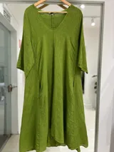 Vestido midi verde de lino, con escote en V, mangas tres cuartos, corte holgado y bolsillos laterales.