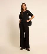 Blusa negra de crepé con cuello redondo, mangas cortas y botones dorados decorativos en los hombros.