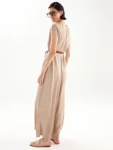 Mono largo color beige con cuello redondo, mangas cortas y cinturón trenzado a la cintura. Presenta aberturas laterales en las piernas y cierre con lazo en el cuello.