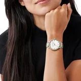 Reloj Michael Kors con caja de acero inoxidable en tono dorado y plateado, esfera blanca con patrón de logo MK grabado y marcadores de hora con cristales. Presenta bisel decorado con cristales y pulsera de eslabones combinados.