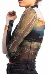 Remera crop top de mangas largas y cuello alto, confeccionada en tejido de red transparente con estampado de paisaje montañoso.