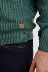 Sweater verde de punto inglés con cuello alto y cierre metálico frontal. Tiene mangas largas y terminaciones en punto canalé.