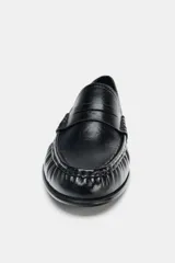 Mocasín plano de cuero negro con detalle de antifaz, copete subido y acabado fruncido en la parte delantera.
