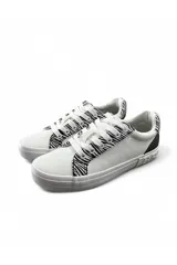 Championes deportivos color blanco con detalles estampados animal print tipo cebra en los laterales y talón, cordones anchos y suela de goma.