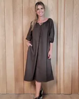 Vestido midi de corte holgado, confeccionado en tela color marrón, con escote redondo y cordón ajustable frontal. Presenta mangas tres cuartos abullonadas con puños elásticos y bolsillos laterales.