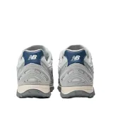 Championes New Balance modelo 204L, de estilo running retro con diseño multicapa. Presentan una combinación de tonos grises en la capellada de gamuza y malla, con el logo N en azul oscuro y detalles en el talón. La suela es de EVA con diseño inspirado en los años 2000.