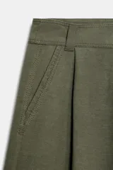 Pantalón cargo de tiro bajo color verde militar, con pinzas delanteras, pernera recta, bolsillos frontales y bolsillos laterales de plastrón. Cuenta con cierre frontal de cremallera y botones.
