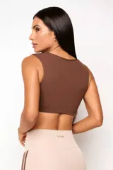 Top deportivo de entrenamiento con escote redondeado y espalda tipo nadador, confeccionado en poliamida tecnológica de alto rendimiento. Cuenta con forro interno y abertura para colocar almohadillas.