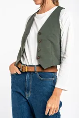 Chaleco verde militar con escote en V, corte al cuerpo y cierre frontal con botones marrones.