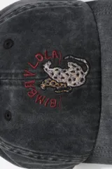Gorra de algodón con efecto lavado, diseño clásico de seis paneles con visera curva. Presenta un bordado frontal con motivos de animales y texto en color rojo.