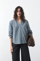 Camisa de algodón con estampado de cuadros vichy en tonos azul y blanco. Presenta escote en V con cierre frontal de botones, mangas largas con puños y un corte levemente holgado con frunces en hombros y espalda.