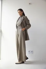 Saco corto entallado de lana fina, con cuello solapa, manga larga y cierre frontal con botones. Presenta un diseño clásico con textura de espiga en tonos tierra.