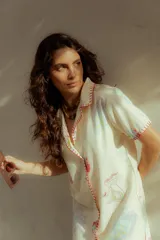 Vestido corto color crema con estampado de motivos marinos en tonos pastel, cuello camisero, cierre frontal con botones y bordado a mano en rojo en cuello, mangas y botonera.