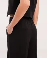 Pantalón de vestir negro de corte palazzo con elástico en la pretina trasera, cierre delantero y broche interno.