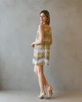Vestido corto de silueta relajada, completamente bordado en lentejuelas con diseño de franjas horizontales en tonos dorados y plateados. Presenta escote redondo y breteles anchos.