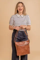 Bandolera mediana de cuero sintético color negro, con correa regulable, bolsillo frontal con cierre y compartimento principal.