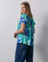 Blusa de seda fría con estampado floral en tonos azules y verdes. Cuello redondo con frunce y mangas cortas amplias con terminación fruncida.