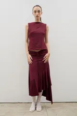 Falda midi de color bordó, con diseño de frunce central ajustable y ruedo irregular con volado lateral.