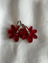 Aros de argolla metálica con dije colgante en forma de flor de acrílico color rosado.