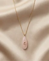 Collar de acero con baño de oro, compuesto por una cadena fina y un dije en forma de gota con piedra natural de cuarzo rosa y una circonia central pequeña.