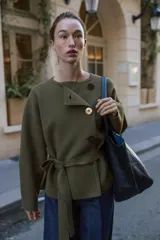 Chaqueta de punto color verde militar, con cuello redondo, manga larga y cierre frontal cruzado con botones. Incluye un cinturón del mismo tejido para ajustar en la cintura.