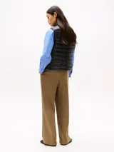 Chaleco negro de nailon con relleno de plumón, cuello mao, cierre de cremallera, bolsillos laterales con cremallera y logo de Tommy Hilfiger estampado en el pecho.