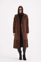 Tapado largo de gamuza color chocolate con detalles de corderito en solapas, puños y ruedo. Presenta cierre frontal con botones y corte recto.