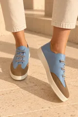 Championes de cuero vacuno color celeste con puntera de gamuza marrón, suela de goma y cordones elásticos.