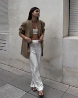 Collar con dije colgante de forma orgánica e irregular, acabado dorado, suspendido de un cordón negro de algodón natural.