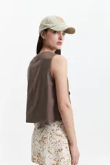 Chaleco corto color marrón topo, con escote en V asimétrico y cierre cruzado con botones.