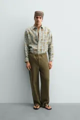 Camisa de corte relajado confeccionada en tejido fluido con estampado geométrico en tonos azules y ocres. Presenta cuello solapa, cierre frontal de botones y manga larga con puños abotonados.