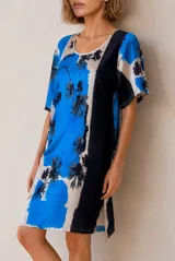Vestido corto de corte recto y holgado, con mangas cortas y cuello redondo. Presenta un diseño estampado con bloques de color en tonos azul, blanco y negro, con detalles florales.