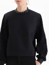 Buzo de calce regular con cuerpo de tela lisa y mangas largas de tejido calado con textura. Presenta escote redondo y puños ajustados.