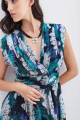 Vestido corto sin mangas con escote en V cruzado y frunces. Confeccionado en viscosa estampada con motivos florales y detalles en lurex plateado. Presenta un recorte ajustado en la cintura y cierre invisible lateral.