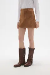 Falda mini de corte recto confeccionada en gamuza sintética color marrón, con cierre frontal de botón y presillas para cinturón.
