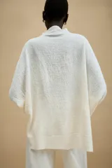 Jersey de punto con textura, color tostado, de cuello subido y manga larga. Presenta un diseño holgado con bajo asimétrico y aberturas laterales.
