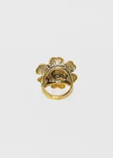 Anillo dorado con forma de flor de seis pétalos con centro circular texturizado. Diseño vintage.