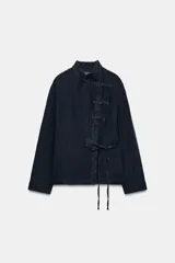 Blusa de lino color azul marino, de manga larga y cuello subido, con cierre frontal cruzado mediante nudos de tela y tiras para lazar en la cintura.