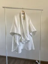 Ruana de diseño estructurado confeccionada en tela tipo tapiz con textura cuadriculada, de corte amplio y caída fluida.