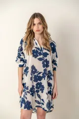 Camisa larga de color blanco con estampado de flores azules, cuello en V y mangas largas.