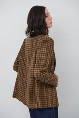 Blazer de paño con estampado de cuadros en tonos marrones, con solapas clásicas, hombreras, cierre frontal con un botón y botones decorativos en los puños.