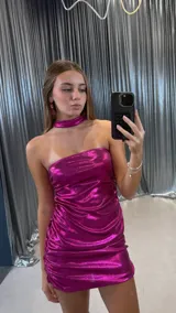 Vestido corto fucsia de lurex, con escote strapless y diseño fruncido en los laterales. Incluye un choker a juego.